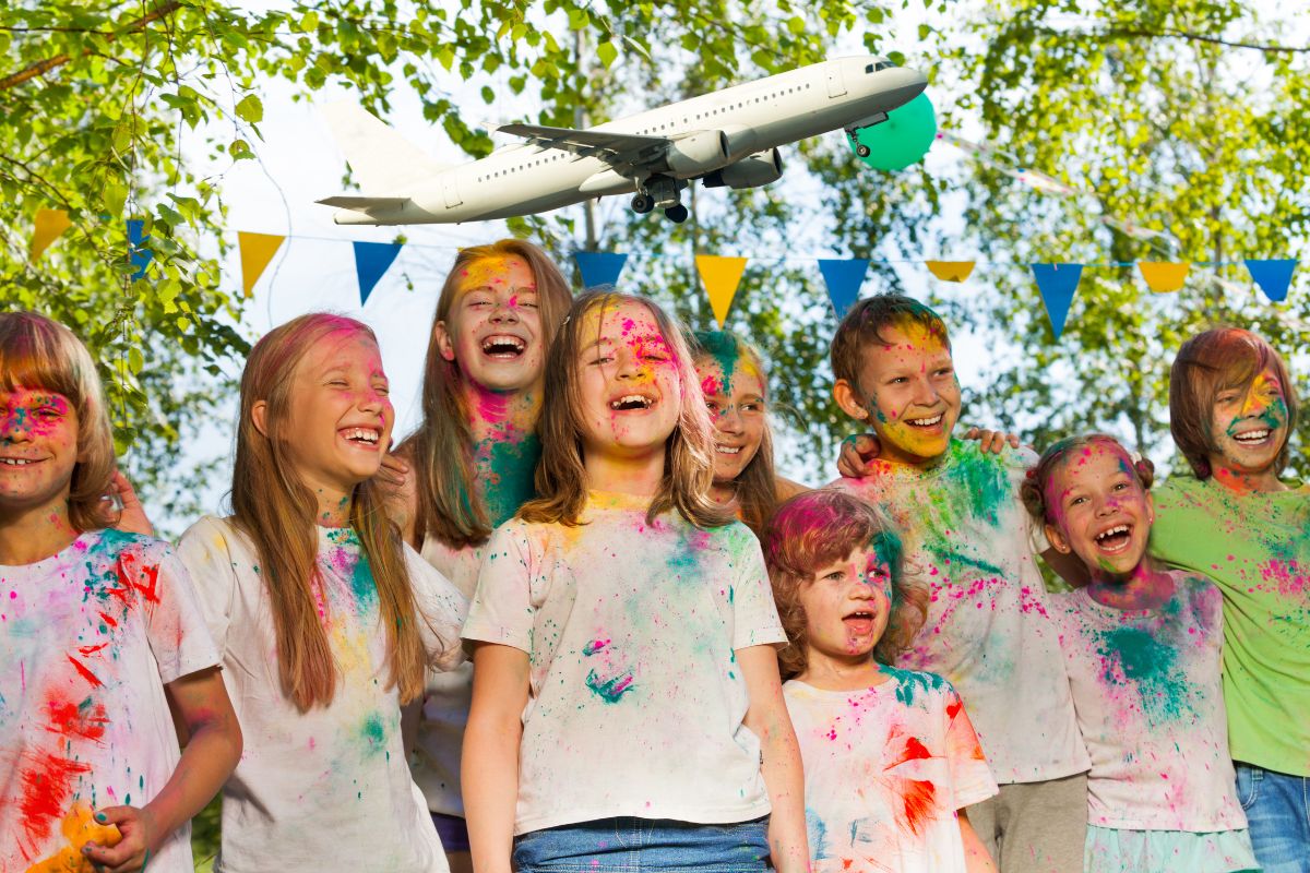 Des enfants joyeux avec des vêtements colorés et un avion en arrière-plan.