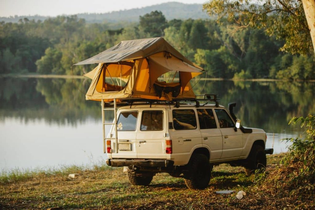 Voiture avec tente de toit au bord d'un lac