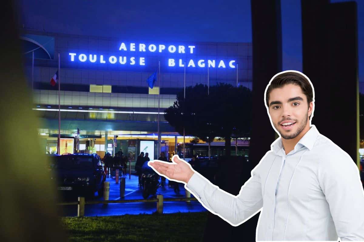Un homme devant l'aéroport de Toulouse Blagnac la nuit.