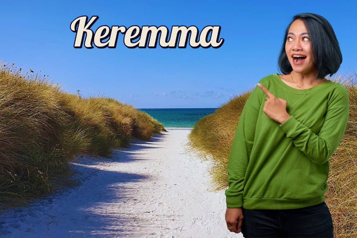 Une femme en pull vert pointant vers une plage de sable blanc à Keremma.
