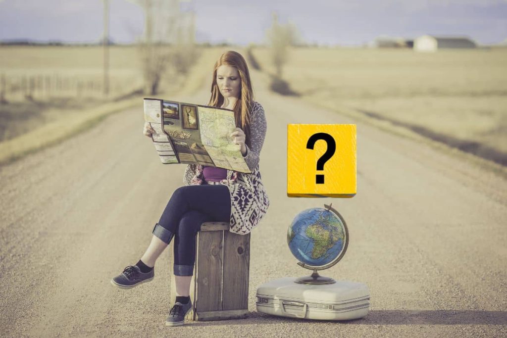 Une jeune femme lit une carte sur une route déserte.