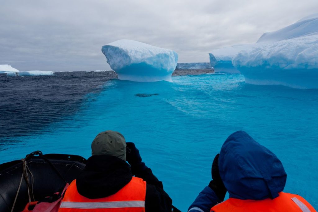 Deux personnes en bateau regardant des icebergs en Antarctique.