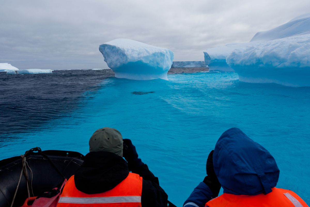 Deux personnes en bateau regardant des icebergs en Antarctique.