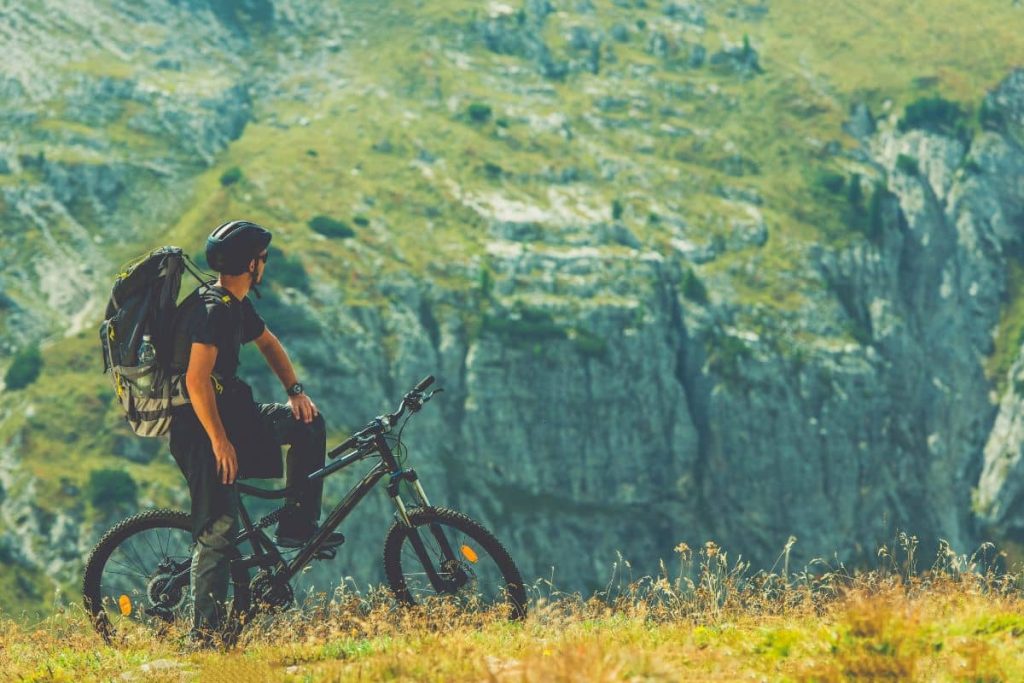 Cycliste avec un sac à dos admirant la vue sur les montagnes.